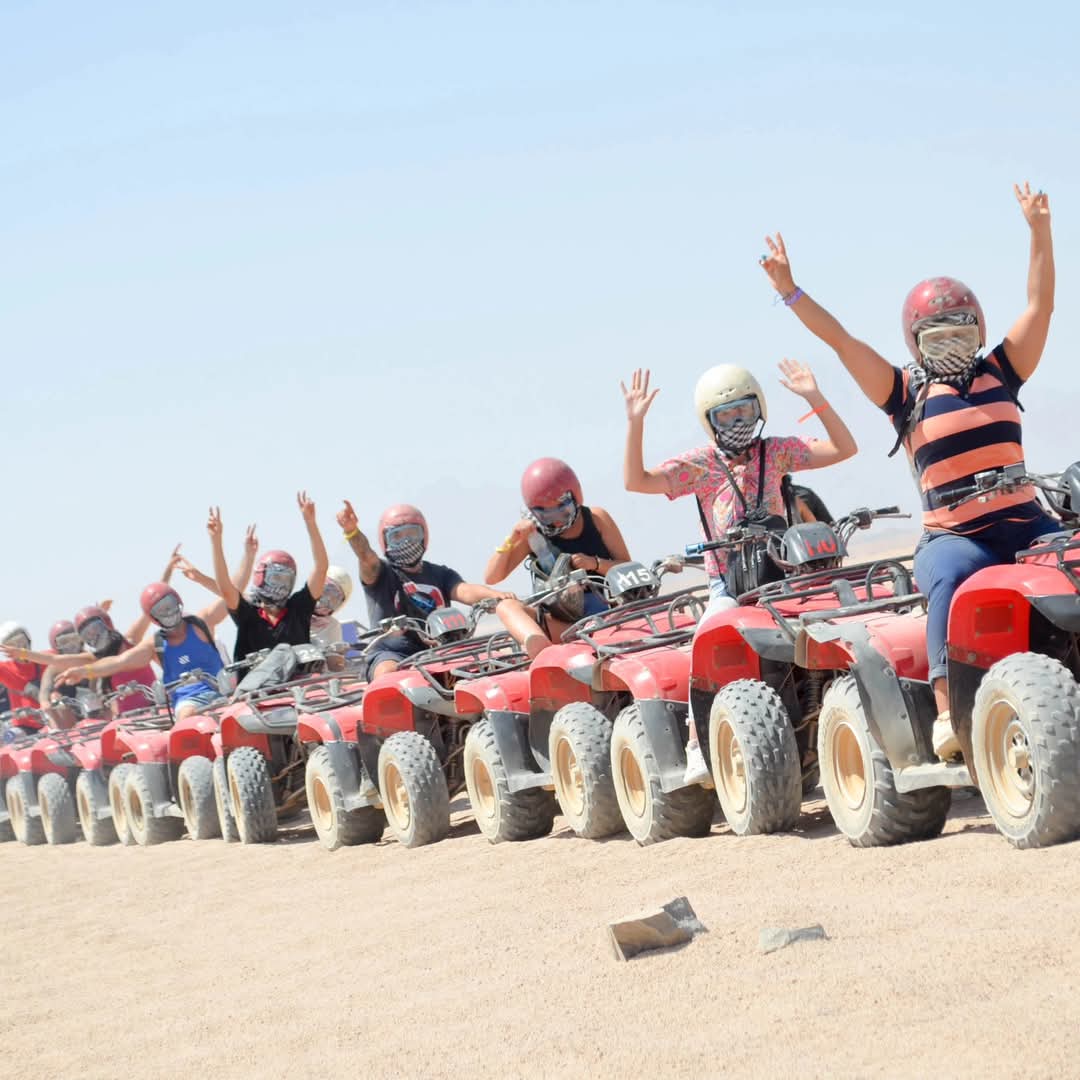 Group of tourists on red quad bikes during desert safari adventure in Hurghada, Egypt – guided ATV tour with Aquila Adventures
