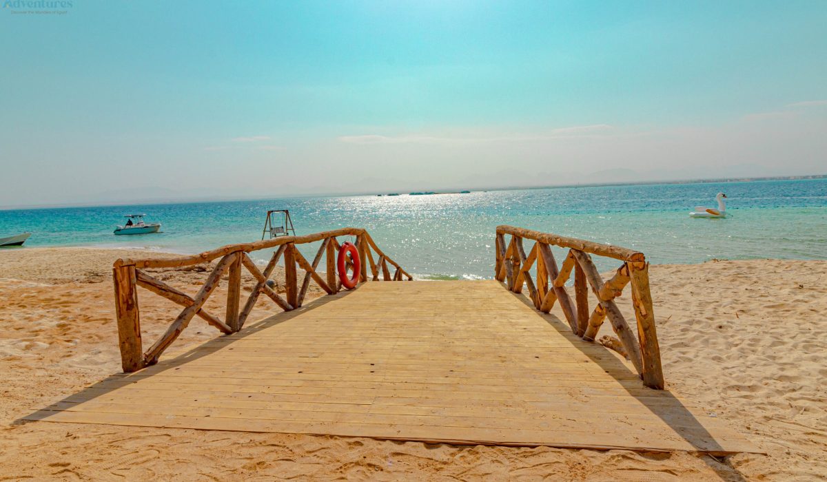 Wooden pier on a white sand beach leading to turquoise Red Sea waters – island trip near Hurghada with Aquila Adventures, Egypt